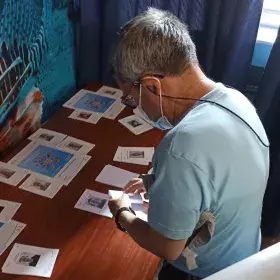 Imagen muestra a Serafín ante una mesa con las papeletas de las personas candidatas a representantes en Junta Directiva. 